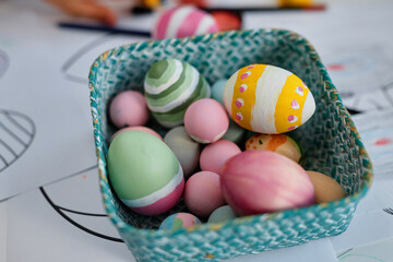 Close up of painted Easter eggs n tiny basket on table in arts and crafts class, copy space