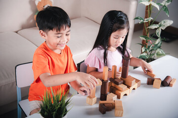 Happy little kids play wood block stacking board game at home, Children boy and girl playing with...