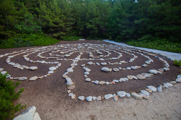 Stone labyrinth in forest clearing, tranquil meditative walking path.







