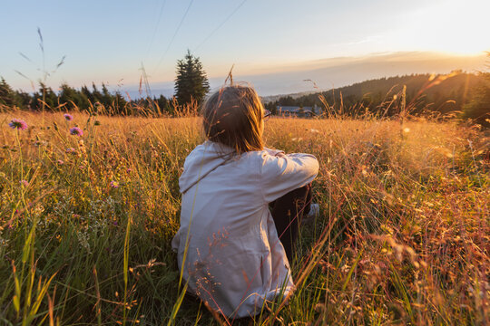 Child enjoying the natural environment on meadow at sunset.