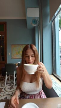 Mujer de pelo cobrizo tomando un cafe con leche grande durante el dia