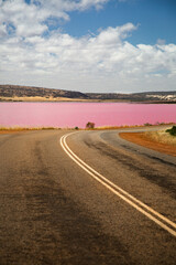 Road to the beautiful salt pink lake, the Hutt Lagoon, with a blue sky and white clouds in Western Australia
