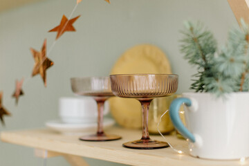 Kitchen table with cups and wineglass, plates and Christmas decorations and little lights and fir