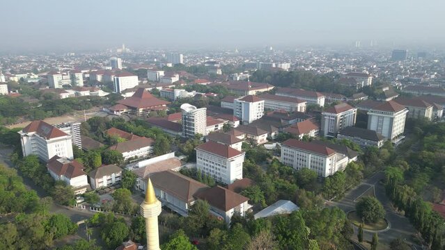 Aerial view of Jogja City with dense buildings development, crowded vehicles traffic in morning sunlight with smog or fog. Population density is displacing agricultural land and forests. Air Pollution