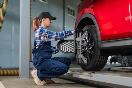 A female auto mechanic makes a camber. Woman working in a car service.