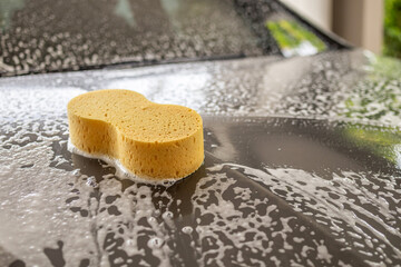 car cleaning and washing with yellow sponge and foam soap
