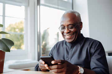 Portrait of a relaxed senior man laughing while using his smartphone at home. Modern lifestyle of the elderly people. 