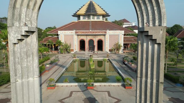 Aerial view of Masjid Kampus Universitas Gadjah Mada or UGM Mosque where Muslims worship with dome and tower surrounded by trees. Eid al-Fitr and Eid al-Adha. Bright Sunlight - During the day.