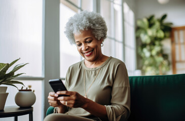 Portrait of a relaxed senior woman laughing while using her smartphone at home. Modern lifestyle of the elderly people.
