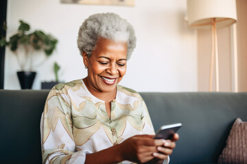 Portrait of a relaxed senior woman laughing while using her smartphone at home. Modern lifestyle of the elderly people. 