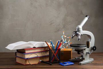Back to school - books and microscope on the wooden desk in the auditorium, Education concept