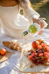 Young beautiful women of 25 years old on an autumn picnic near the lake. Glass of white wine, pastries. Happy models chatting merrily. Sunset.