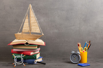 Education is a journey concept, toy boat and books on the table, inspiration for a writing a fairy tale. Elementary school supplies - 660375767