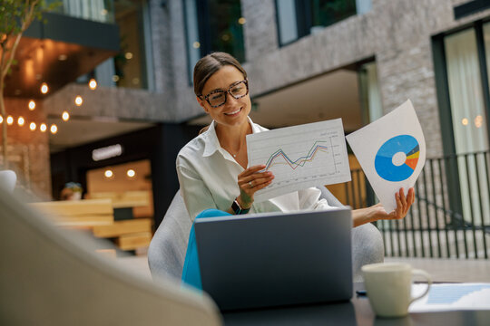 Smiling female manager showing documents to colleagues during online meeting sitting in coworking - Powered by Adobe
