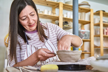 Woman creating a bowl with clay in pottery class. Crafts concept  - obrazy, fototapety, plakaty