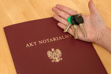 Klucze trzymane w dłoniach nad aktem notarialnym, zakup nieruchomości  - obrazy, fototapety, plakaty