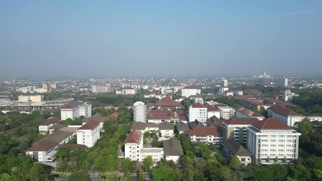 Aerial view of Jogja City with dense buildings development, crowded vehicles traffic in morning sunlight with smog or fog. Population density is displacing agricultural land and forests. Air Pollution
