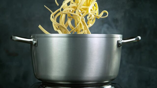 Throwing pasta fettuccine into boiled water in pot, shooting with high speed cinematic camera at 1000 fps