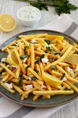 Homemade Greek Fries with Feta and Tzatziki on a Plate, side view.