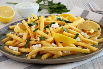 Homemade Greek Fries with Feta and Tzatziki on a Plate, side view.