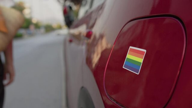 Applying Pride Sticker to Red Car