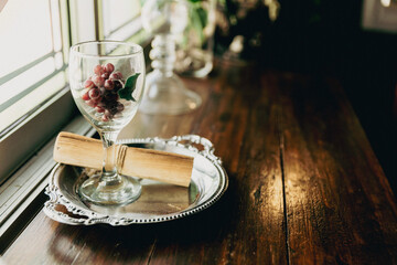 grape in wine glass with vintage roll of paper on Table. festive dinner setting with flowers....