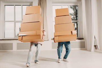 Young family couple man and woman moving with heavy cardboard boxes to new apartment.