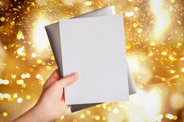 Obraz premium Christmas Blank. Greeting Card with Envelope in Hand on Shiny Light Background. Gift Certificate Postcard. Sale Flyer. Copy Space.Empty. 
