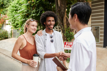 Happy diverse young couple having meeting with real estate agent