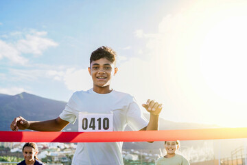 Teenager man runner crossing finish line during race marathon competition - Children and sport life...