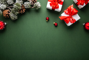 Merry Christmas and Happy Holidays greeting card, frame, banner. New Year. Noel. Red Christmas ornaments and gift on green background top view. Winter xmas holiday theme. Flat lay