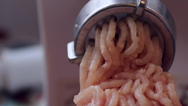 Preparing ground meat using an electric meat grinder, close-up. view of the meat grinding process with kitchen appliances. Grinding raw chicken meat at home, accelerated video