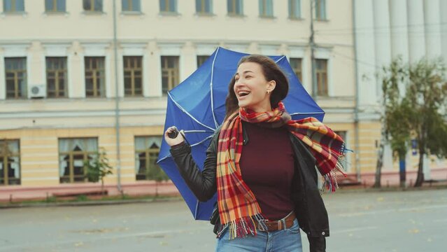 Young attractive woman in good mood, despite the gloomy weather, has her umbrella blown away by the gusts of wind. Lonely female waiting in windy weather.