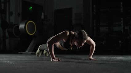 Athletic woman fighter in gym, strong woman performs explosive push ups, makes a clapping push in slow motion, motivation.
