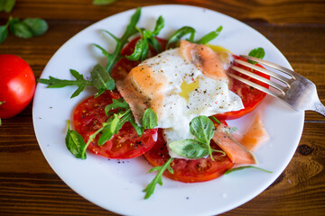 Cooked poached egg with herbs, lightly salted salmon and tomatoes with spices .