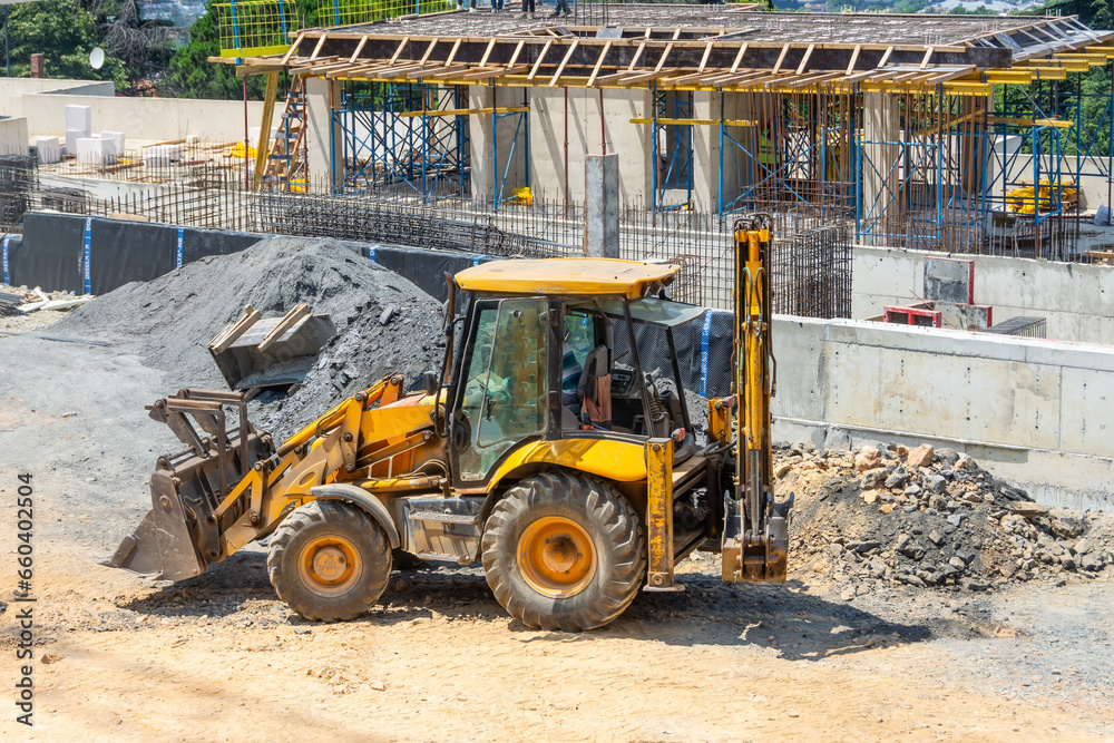 Wall mural the excavator backfills the pit with the front bucket. moves soil around the construction site. foun