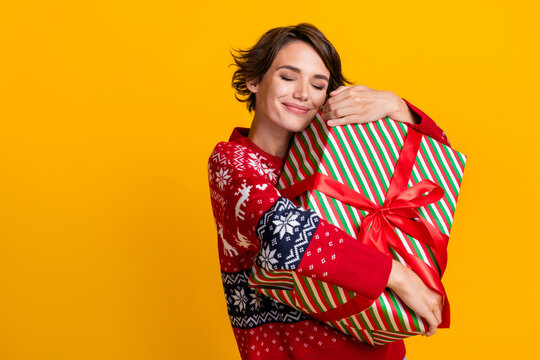 Photo of satisfied girl with bob hairstyle dressed sweatshirt embrace present box on christmas eve isolated on yellow color background