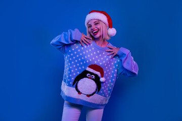 Photo of cute adorable woman santa elf wear ugly print pullover having fun xmas party isolated blue...