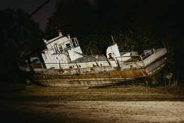 An old abandoned rusty ship on the beach on the sand. The yacht is washed ashore