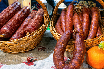 Homemade Ukrainian sausage in baskets on traditional embroidered tablecloth is sale at the market.