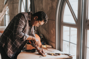 a Young man Carpenter works on woodworking machinery in a carpentry shop. The workshop looks professional, highly skilled, and the craftsmen are true craftsmen.