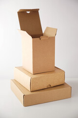 Cardboard boxes of different shapes are arranged on each other on a light background. Vertical image.