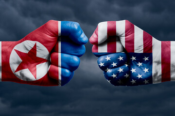 KOREA NORTH vs USA confrontation, religious conflict. Men's fists with painted flags of KOREA NORTH and USA.