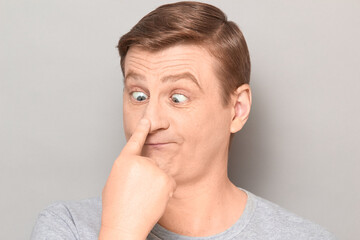 Portrait of funny man making goofy face, touching his nose with finger