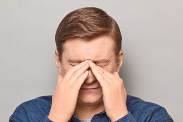 Portrait of unhappy tired man touching bridge of nose, squinting eyes