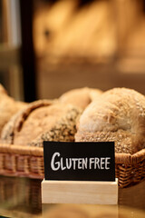 Vertical closeup of fresh breads in artisan bakery with Gluten free sign, copy space