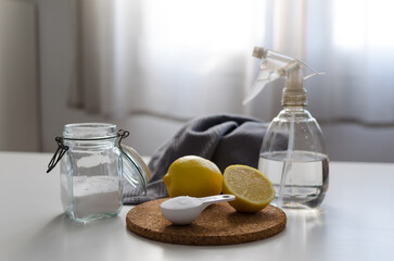 Eco spray bottle filled with water and vinegar and a cleaning cloth and soda and lemons on a table...