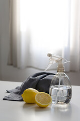 Spray bottle filled with water and vinegar and lemon essence and a cleaning cloth on a table...