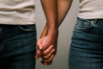 Couple in jeans wear holding hands. Close up of caucasian couple holding hands. Love and care concept.