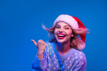 Photo of positive lovely girl stylish ugly sweater laughing demonstrating blank space promo isolated on neon light blue color background